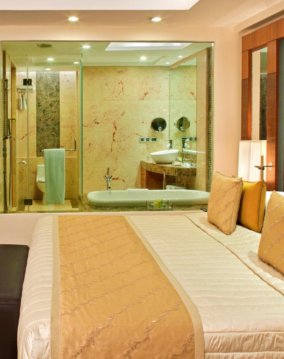 a bedroom with a large bed and a bath tub at Radisson Blu Plaza Delhi Airport in New Delhi a bedroom with a large bed and a bath tub at Radisson Blu Plaza Delhi Airport in New Delhi