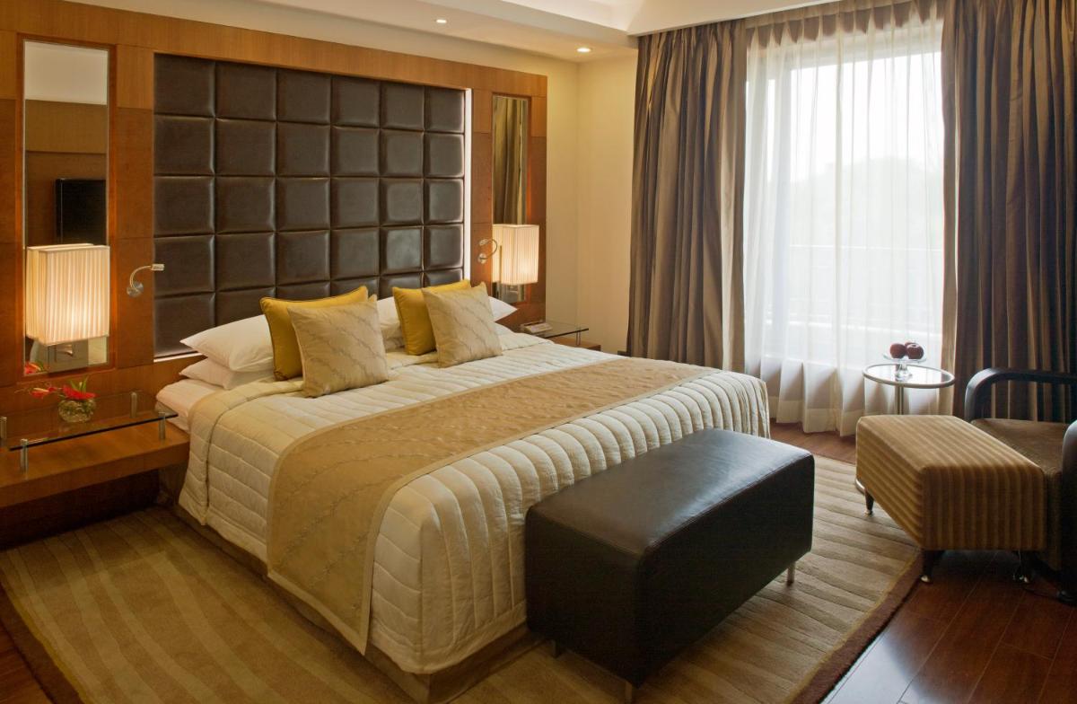 a bedroom with a large bed and a large window at Radisson Blu Plaza Delhi Airport in New Delhi a bedroom with a large bed and a large window at Radisson Blu Plaza Delhi Airport in New Delhi