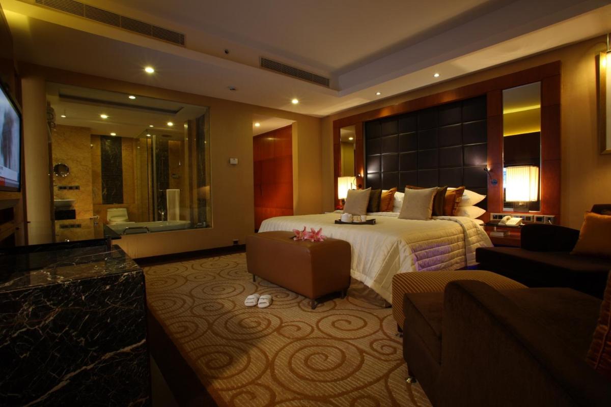 a hotel room with a large bed and a living room at Radisson Blu Plaza Delhi Airport in New Delhi a hotel room with a large bed and a living room at Radisson Blu Plaza Delhi Airport in New Delhi