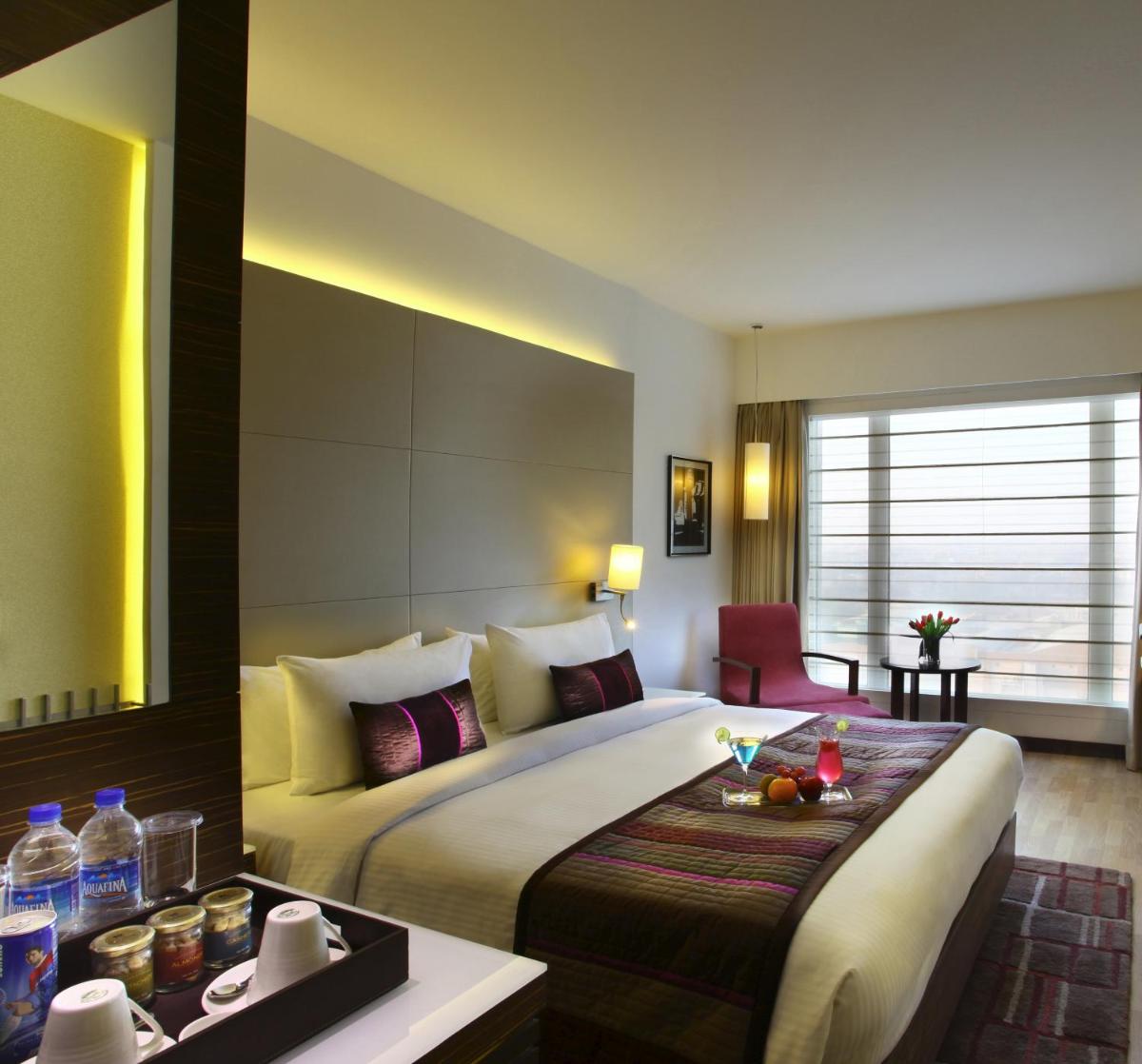 a hotel room with a large bed and a table at Park Plaza Shahdara in New Delhi a hotel room with a large bed and a table at Park Plaza Shahdara in New Delhi