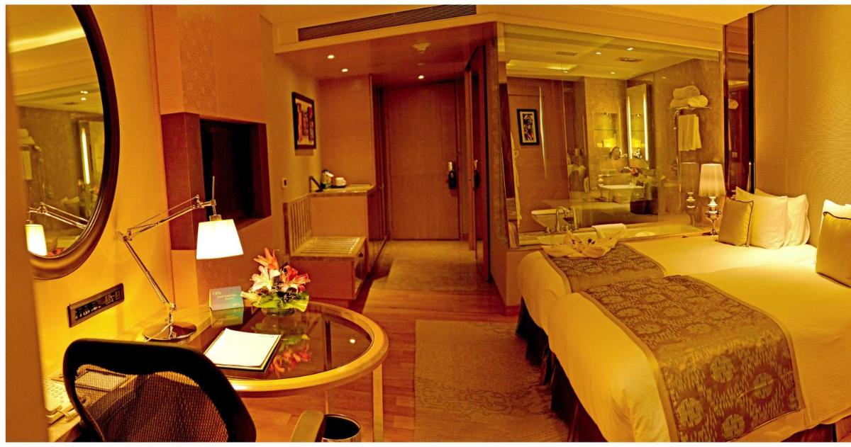 a hotel room with a bed and a table and a bathroom at Radisson Blu Jaipur in Jaipur