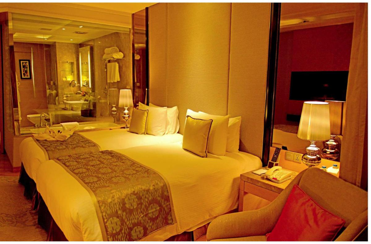 a hotel room with a large bed and a mirror at Radisson Blu Jaipur in Jaipur
