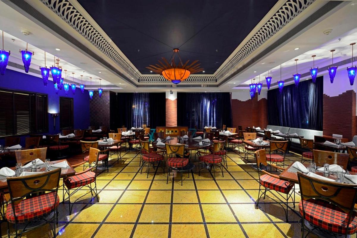a restaurant with tables and chairs in a room at Radisson Blu Hotel Ahmedabad in Ahmedabad