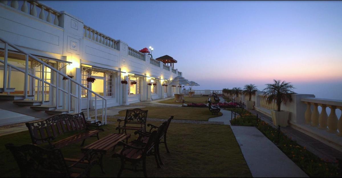 a building with chairs and tables on a patio at dusk at Jaypee Residency Manor in Mussoorie