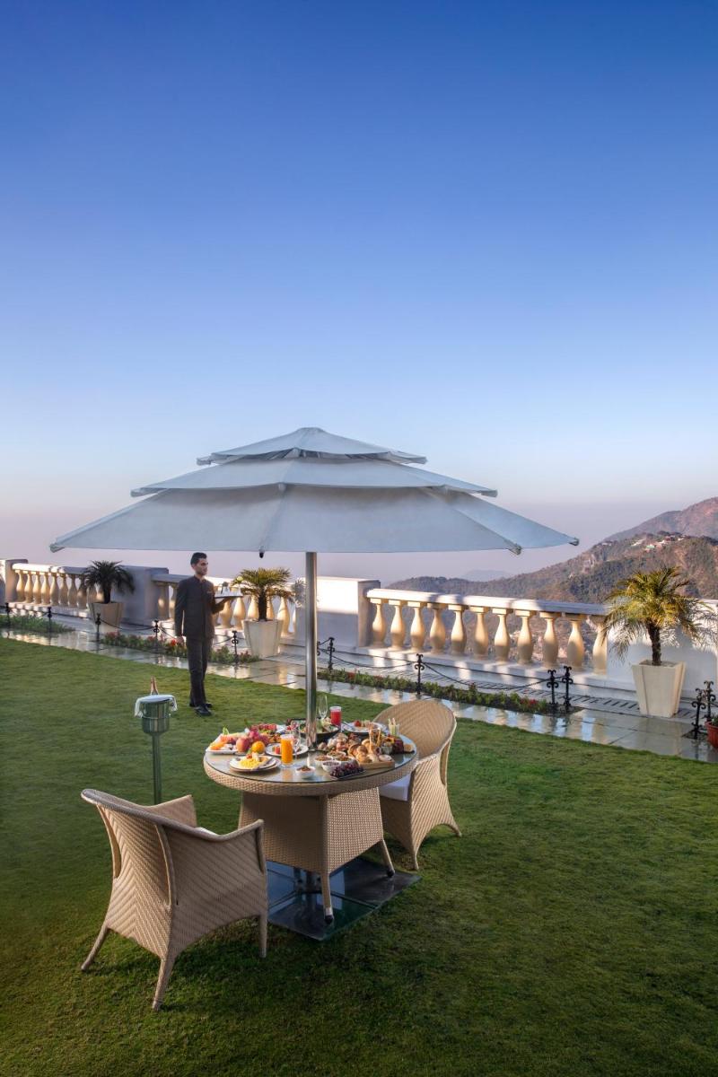 a table and chairs with an umbrella on a lawn at Jaypee Residency Manor in Mussoorie