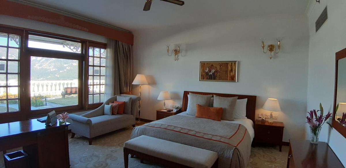 a bedroom with a bed and a chair and a window at Jaypee Residency Manor in Mussoorie