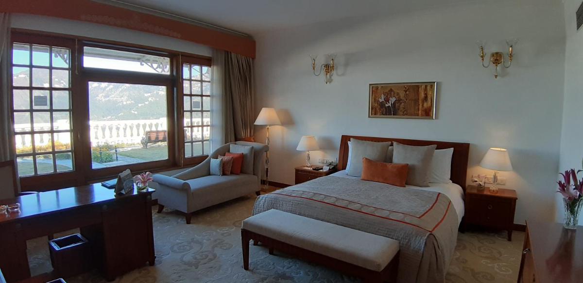 a bedroom with a bed and a chair and a window at Jaypee Residency Manor in Mussoorie