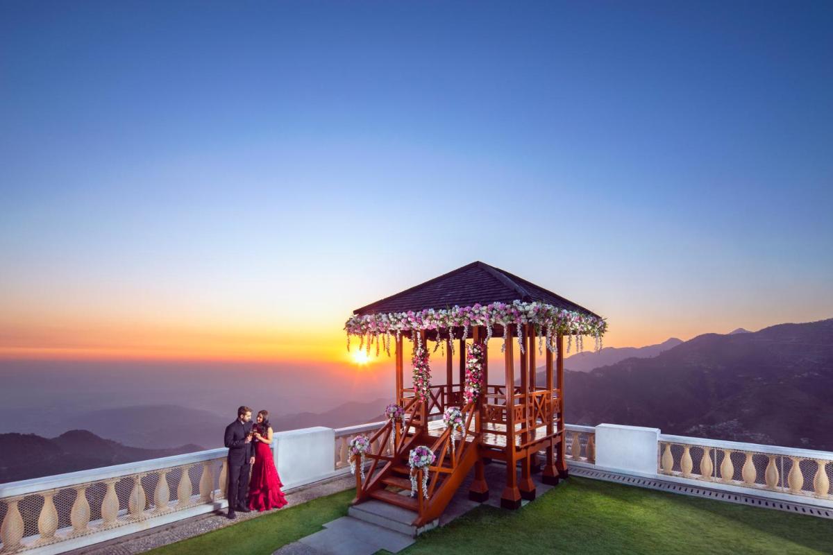 a bride and groom standing next to a carousel at sunset at Jaypee Residency Manor in Mussoorie