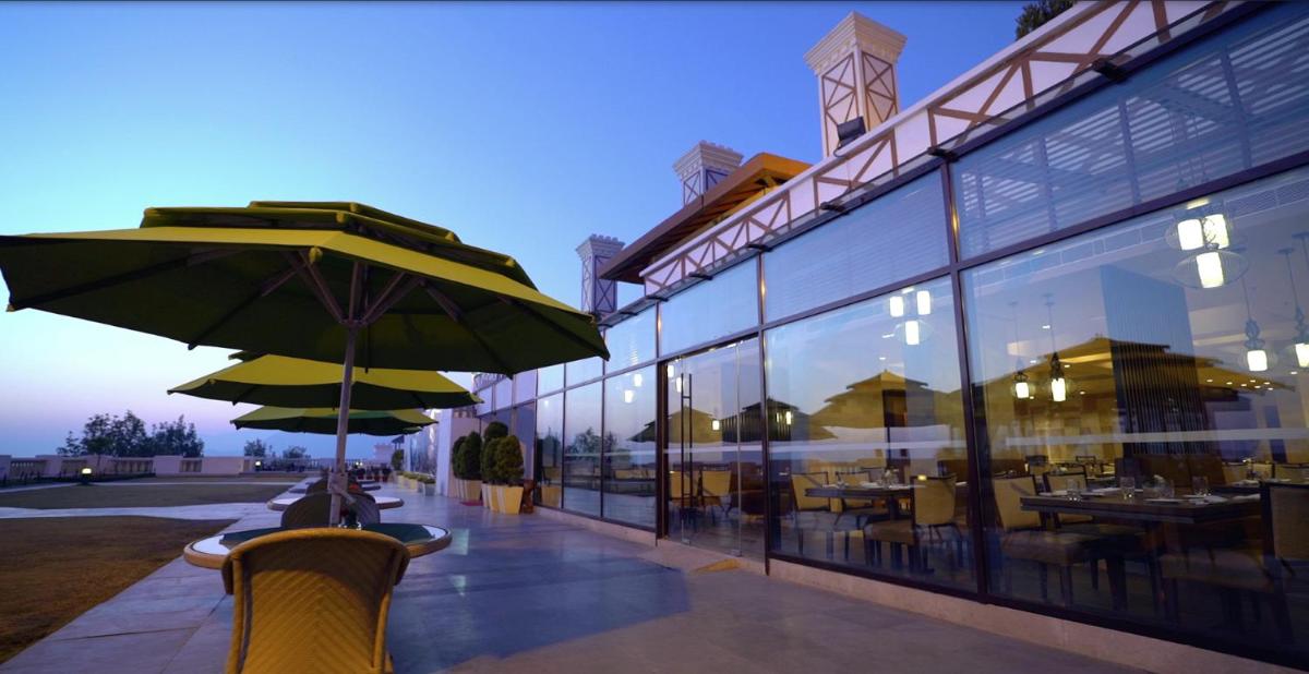 a restaurant with tables and umbrellas in front of a building at Jaypee Residency Manor in Mussoorie