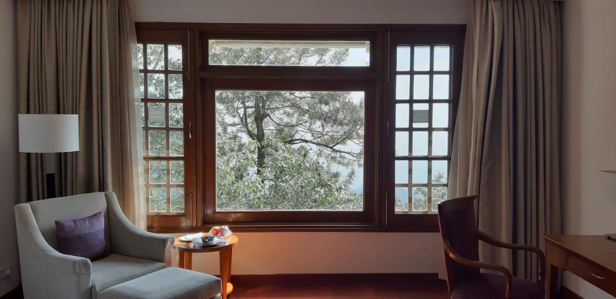 a room with a large window with a chair and a table at Jaypee Residency Manor in Mussoorie