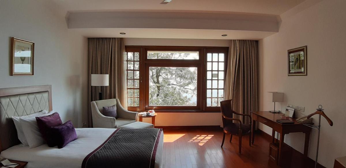 a bedroom with a bed and a desk and a window at Jaypee Residency Manor in Mussoorie