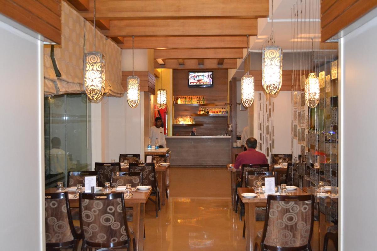 a restaurant with tables and chairs and a man sitting at it at Sayaji Pune in Pune
