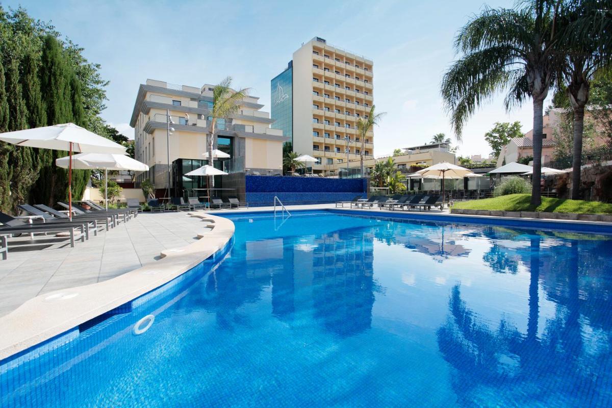 Una gran piscina azul con sillas y sombrillas. en Isla Mallorca & Spa, en Palma de Mallorca