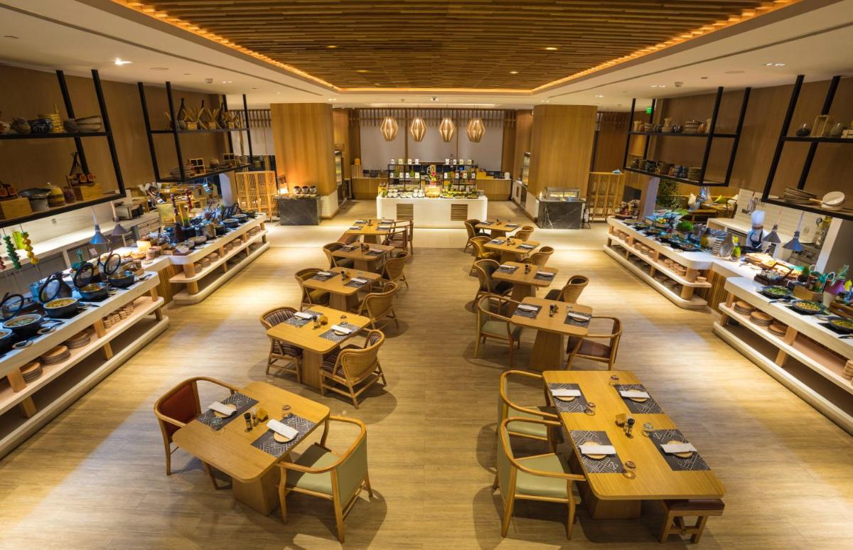 a restaurant with tables and chairs in a room at Novotel Hyderabad Airport in Hyderabad