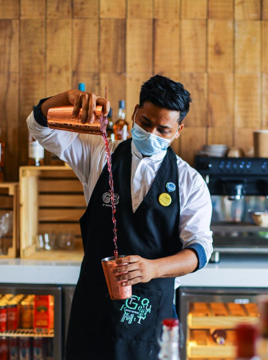a man wearing a mask holding a pot in a kitchen at Novotel Hyderabad Airport in Hyderabad