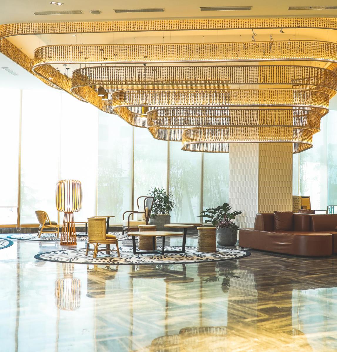 a lobby with a large chandelier and tables and chairs at Novotel Hyderabad Airport in Hyderabad