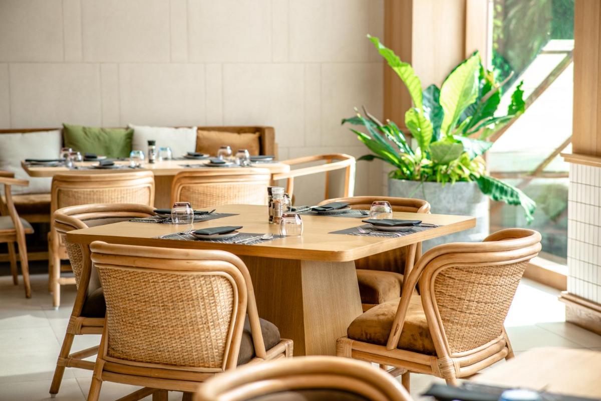 a restaurant with tables and chairs and a plant at Novotel Hyderabad Airport in Hyderabad
