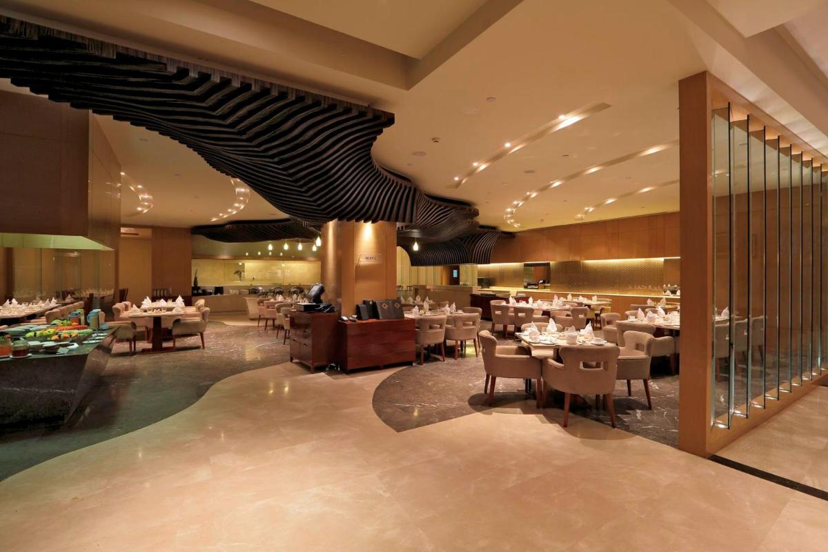 a dining room with tables and chairs in a restaurant at Yashail Hotel Haridwar in Haridwār