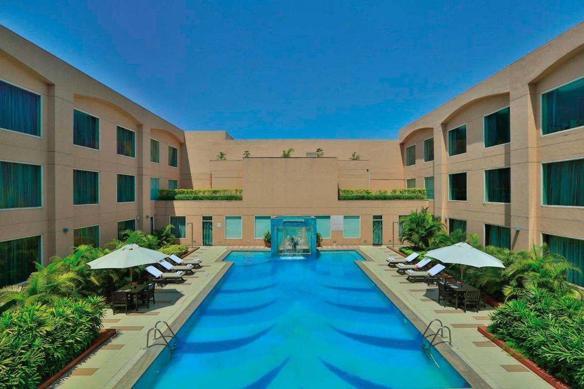 a swimming pool in a hotel with chairs and umbrellas at Yashail Hotel Haridwar in Haridwār