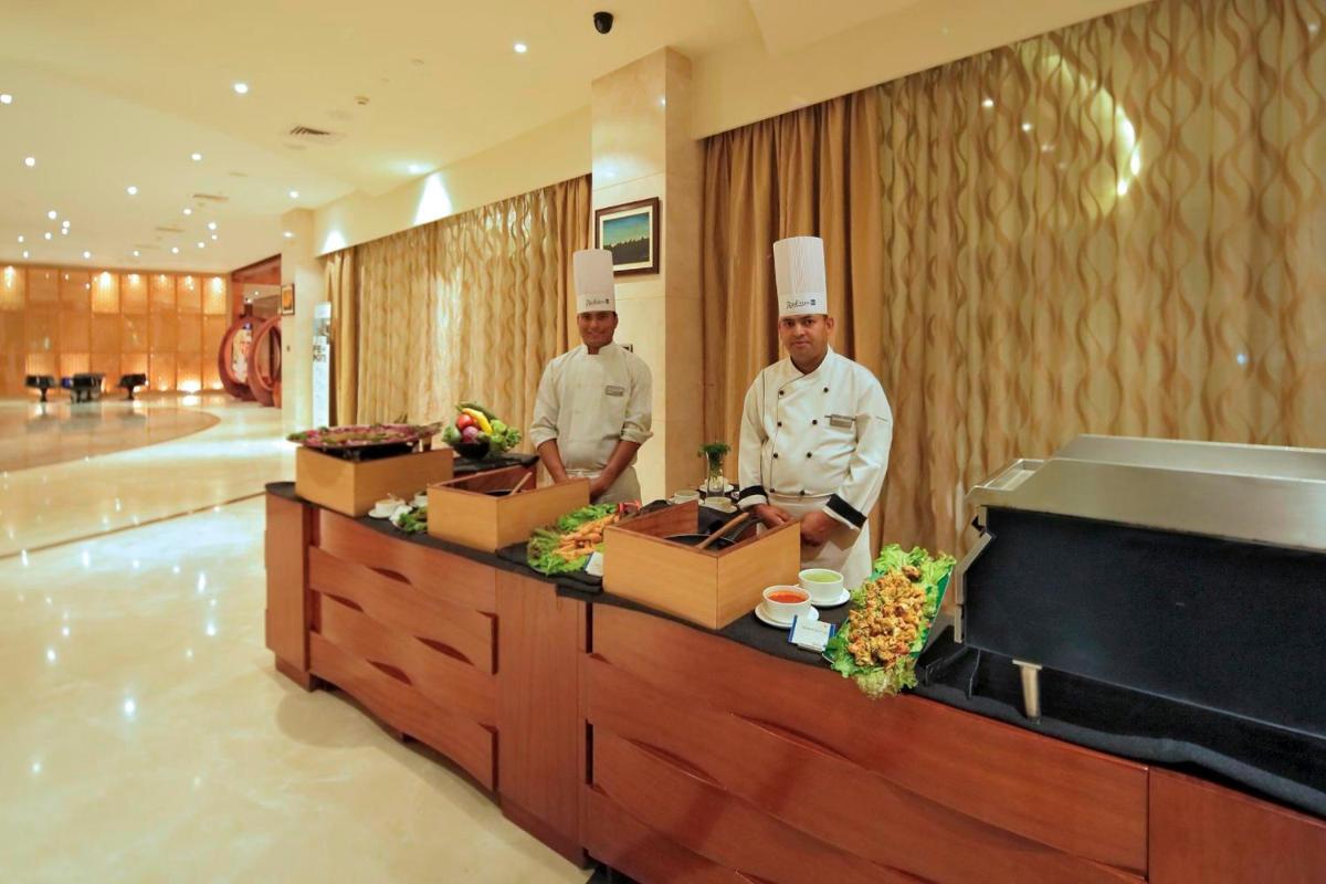 two chefs standing behind a counter in a restaurant at Yashail Hotel Haridwar in Haridwār