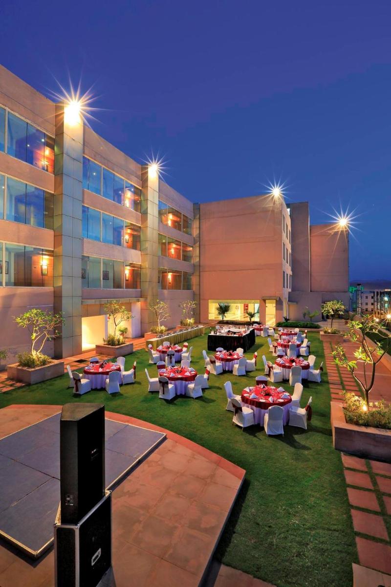 a hotel yard with tables and chairs and a building at Yashail Hotel Haridwar in Haridwār