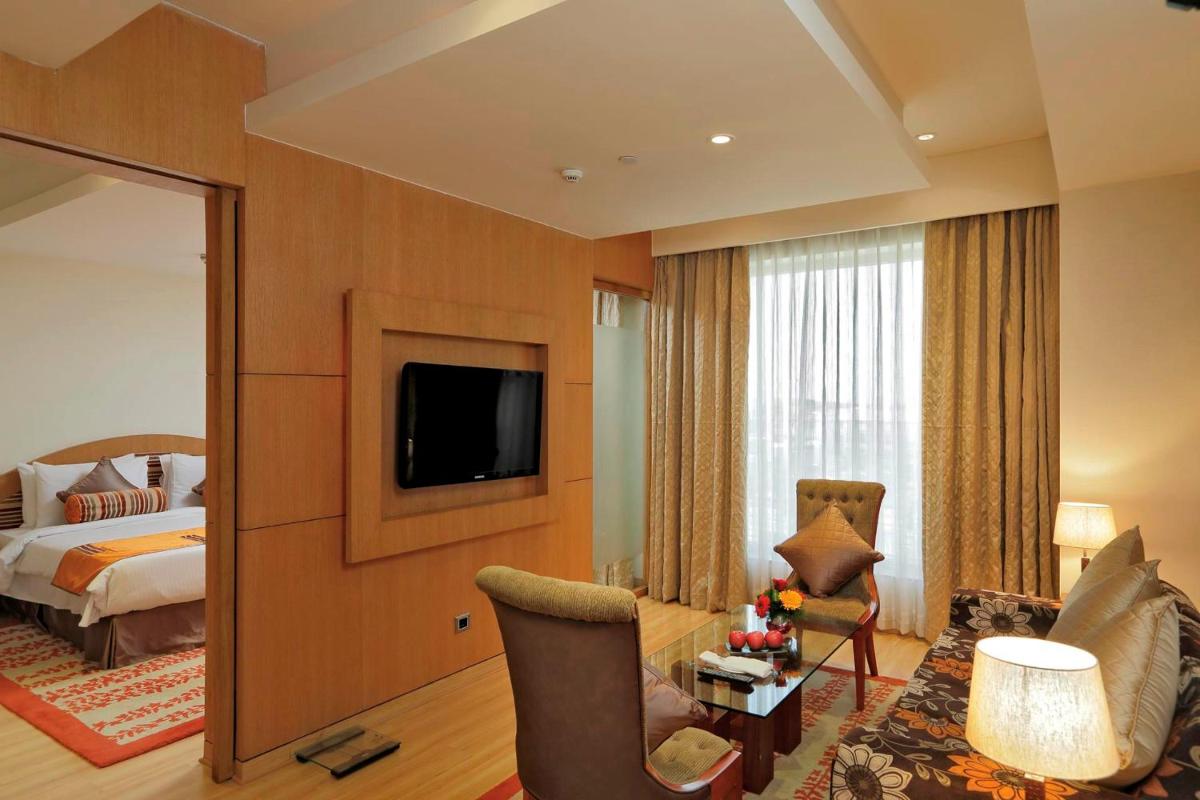 a hotel room with a bed and a television at Yashail Hotel Haridwar in Haridwār