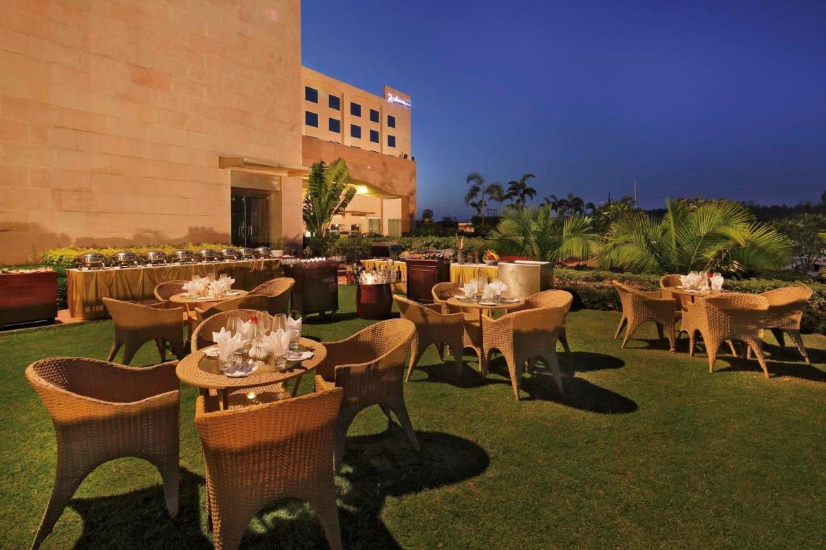 a restaurant with tables and chairs and a building at Yashail Hotel Haridwar in Haridwār