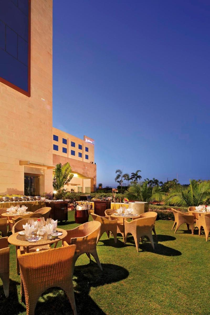 a restaurant with tables and chairs and a building at Yashail Hotel Haridwar in Haridwār