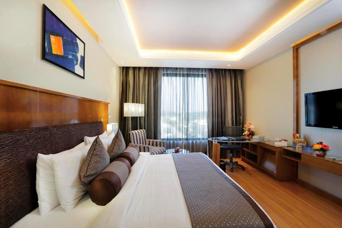 a hotel room with a large bed and a desk at Yashail Hotel Haridwar in Haridwār