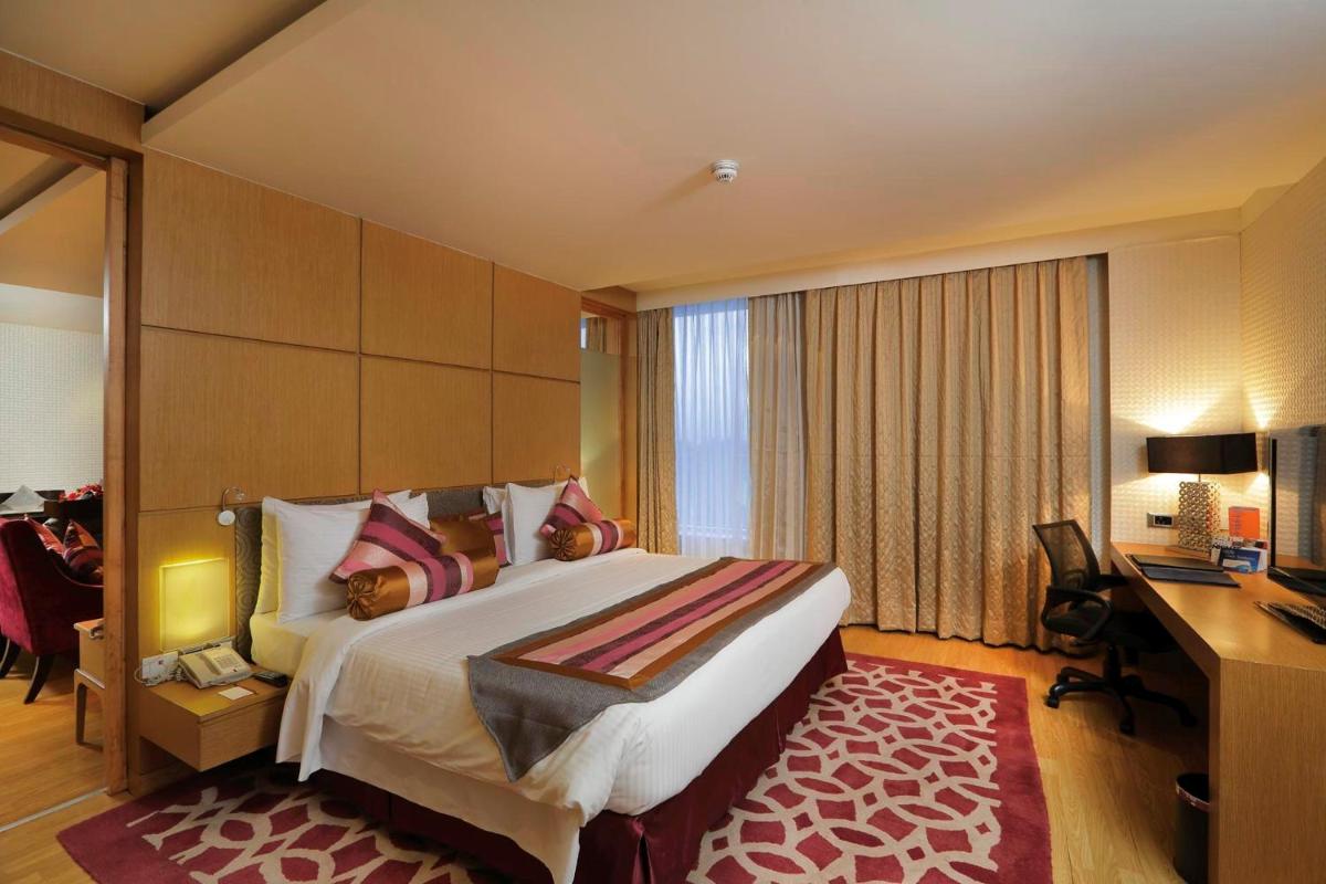 a hotel room with a large bed and a desk at Yashail Hotel Haridwar in Haridwār