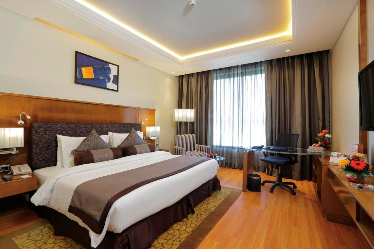 a hotel room with a large bed and a desk at Yashail Hotel Haridwar in Haridwār