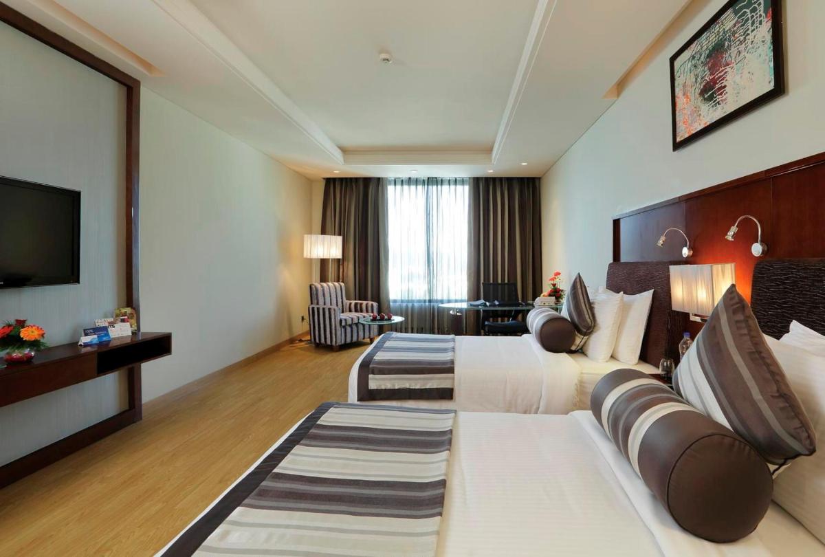 a hotel room with two beds and a television at Yashail Hotel Haridwar in Haridwār
