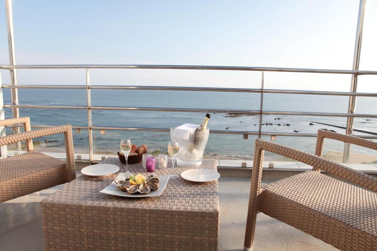 une table avec une assiette de nourriture et un oiseau sur un balcon dans l'établissement Atlantic Hôtel & Spa, à Les Sables-dʼOlonne