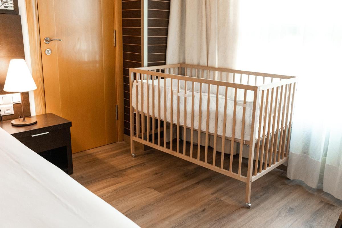 Una cuna en una habitación junto a un dormitorio en Nastasi Hotel & Spa, en Lleida 47 fotos más
