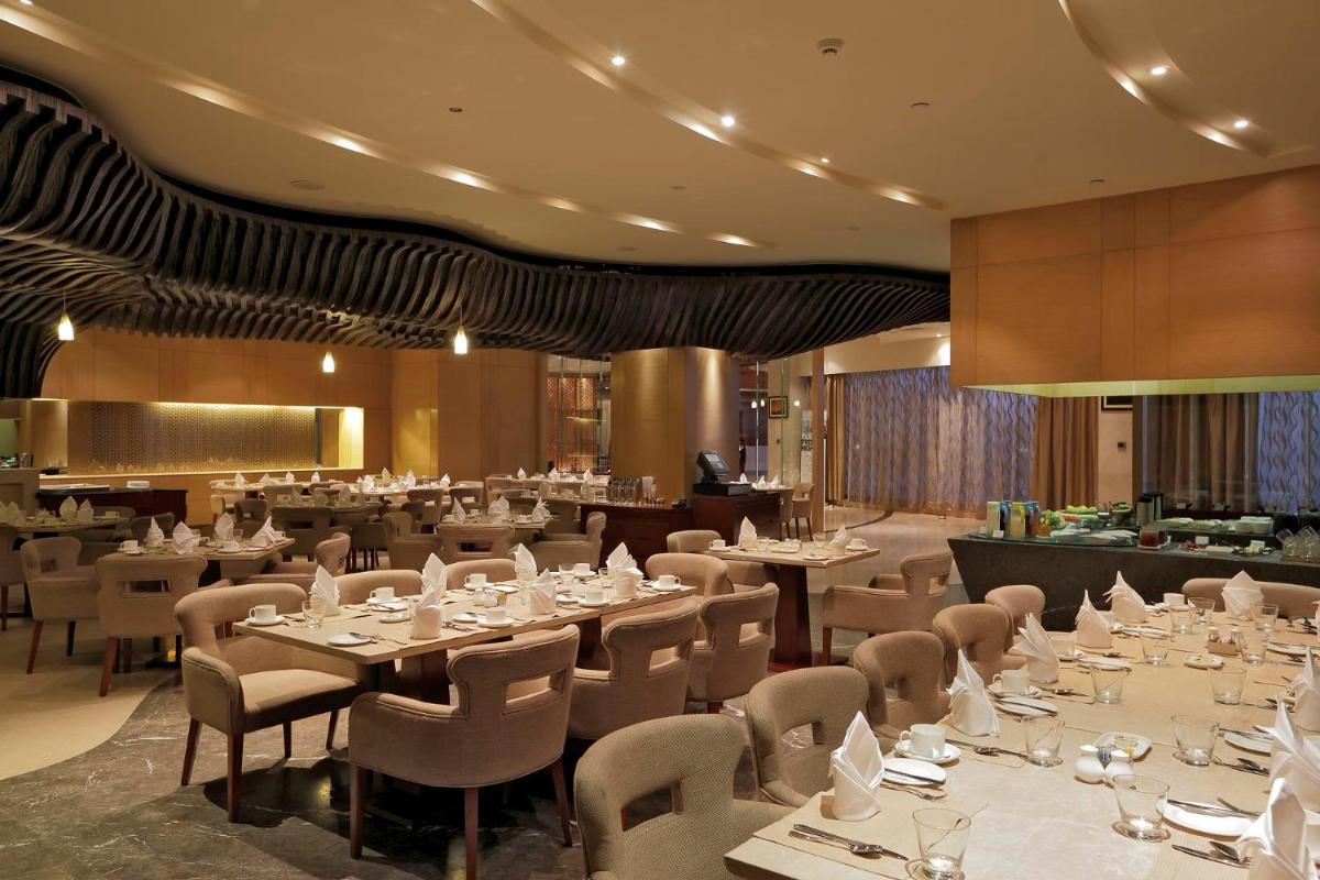 a dining room with tables and chairs and a restaurant at Yashail Hotel Haridwar in Haridwār