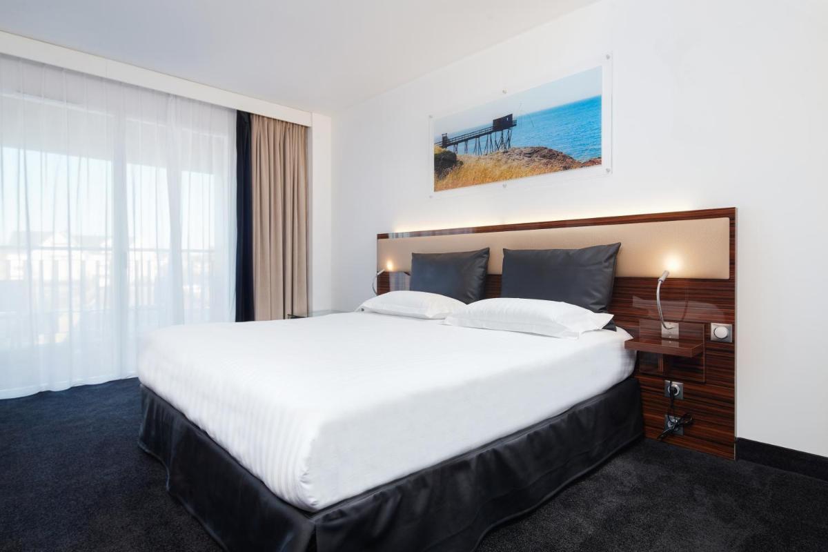 un grand lit blanc dans une chambre d'hôtel dans l'établissement Westotel Pornic Côte de Jade, à Pornic