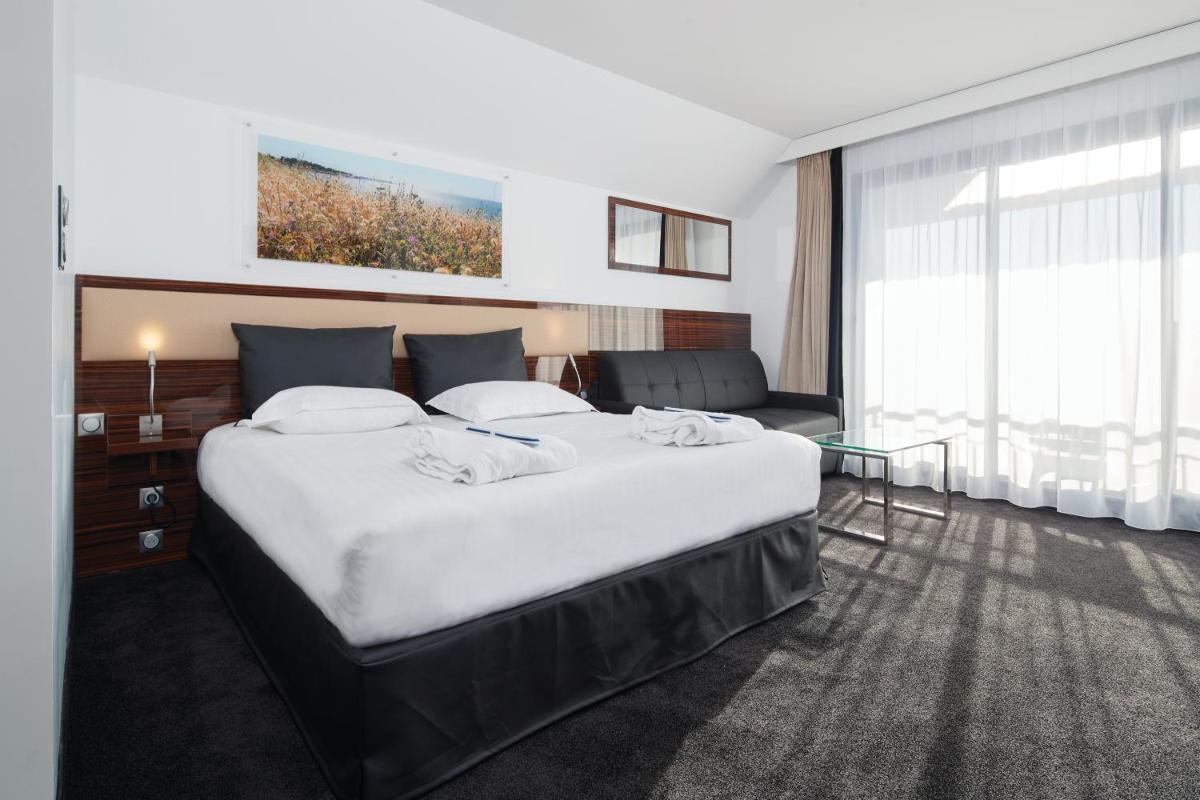 une chambre d'hôtel avec un grand lit et un canapé dans l'établissement Westotel Pornic Côte de Jade, à Pornic