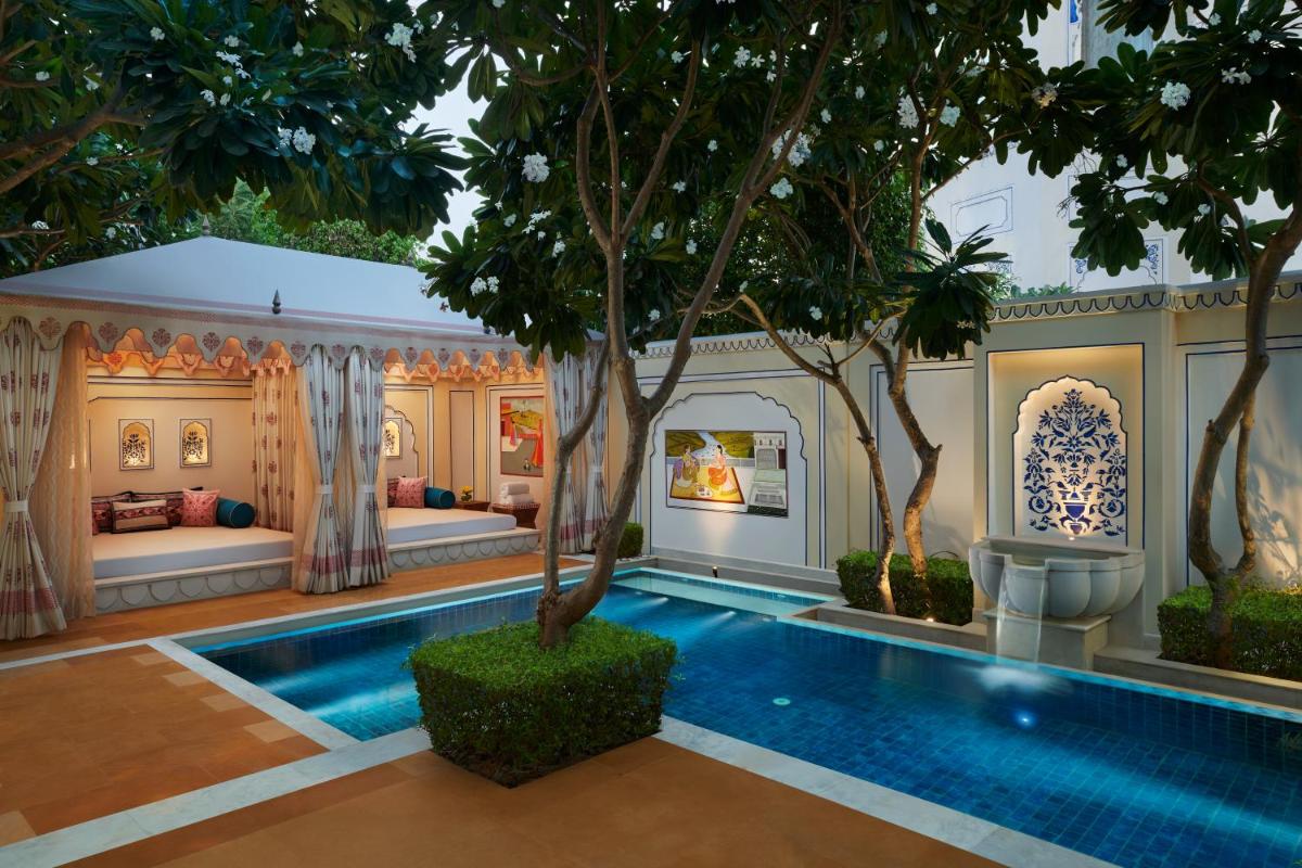 a villa with a swimming pool and a bedroom at The Leela Palace Jaipur in Jaipur