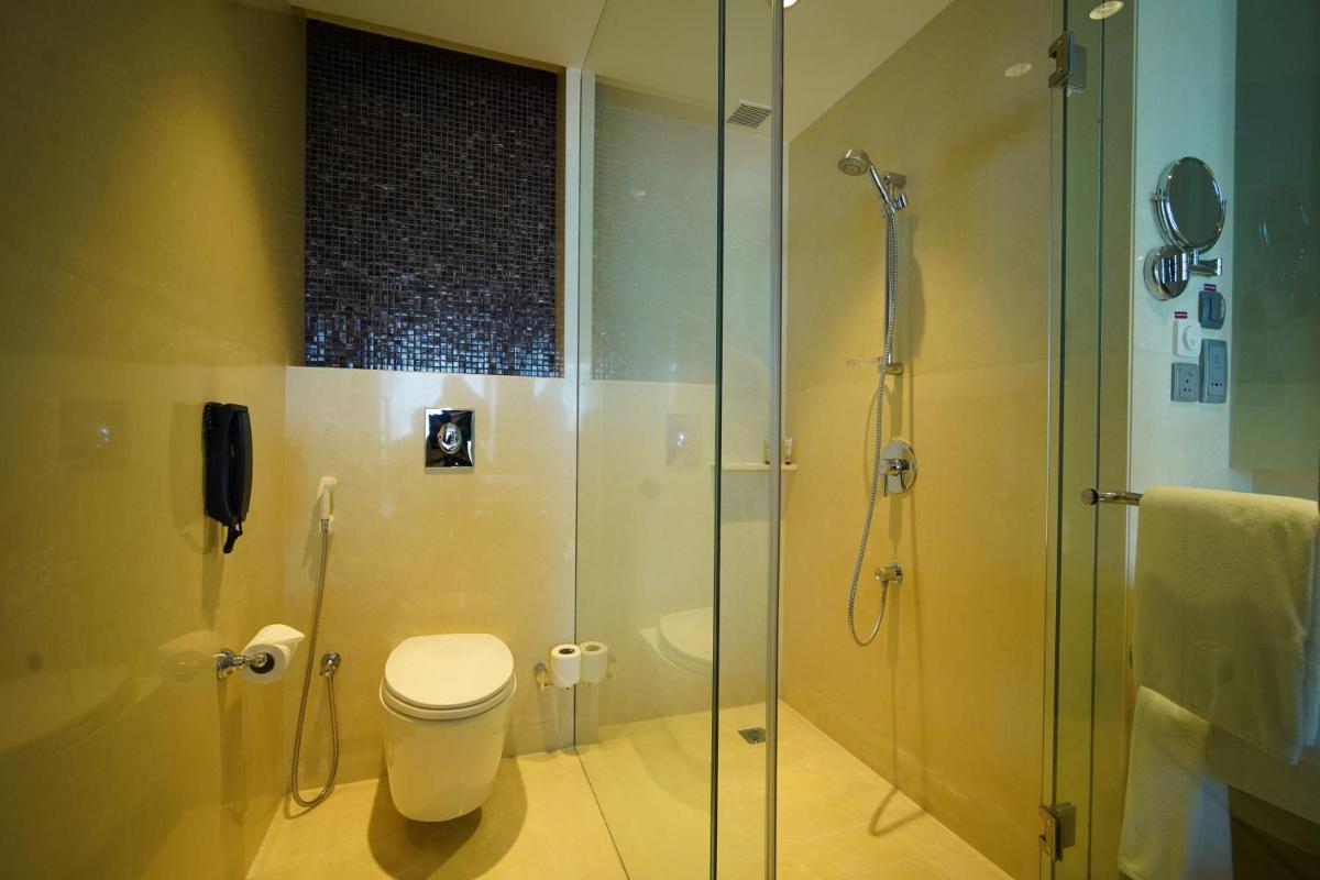 a bathroom with a toilet and a glass shower at Crowne Plaza Kochi by IHG in Cochin