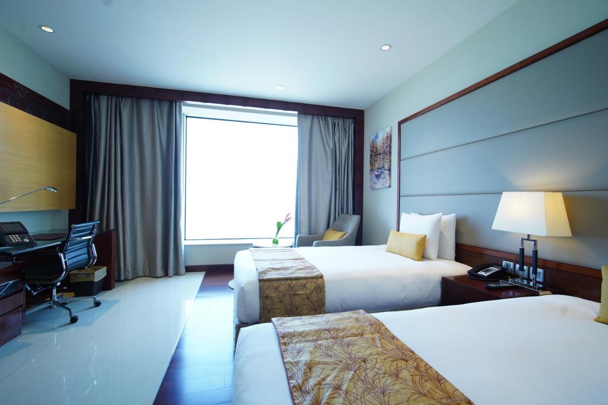 a hotel room with two beds and a desk at Crowne Plaza Kochi by IHG in Cochin