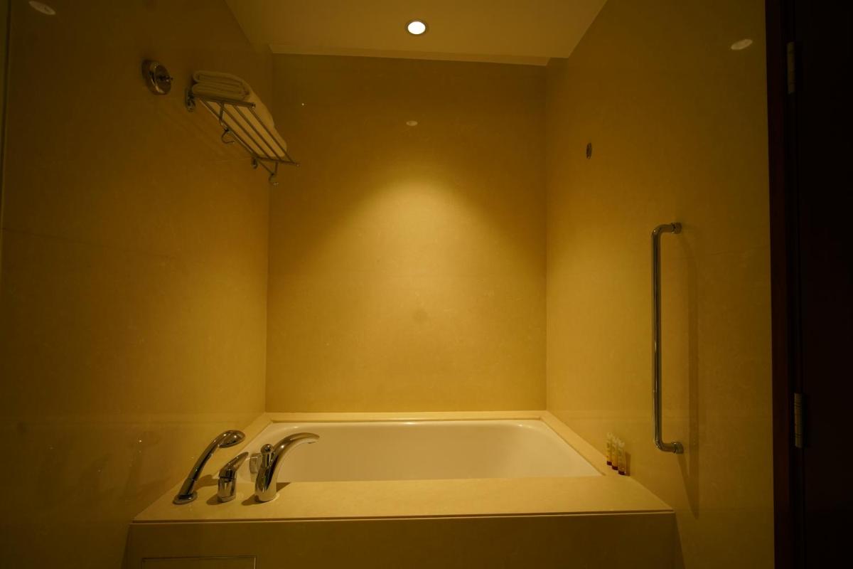 a bathroom with a tub with a light on the wall at Crowne Plaza Kochi by IHG in Cochin