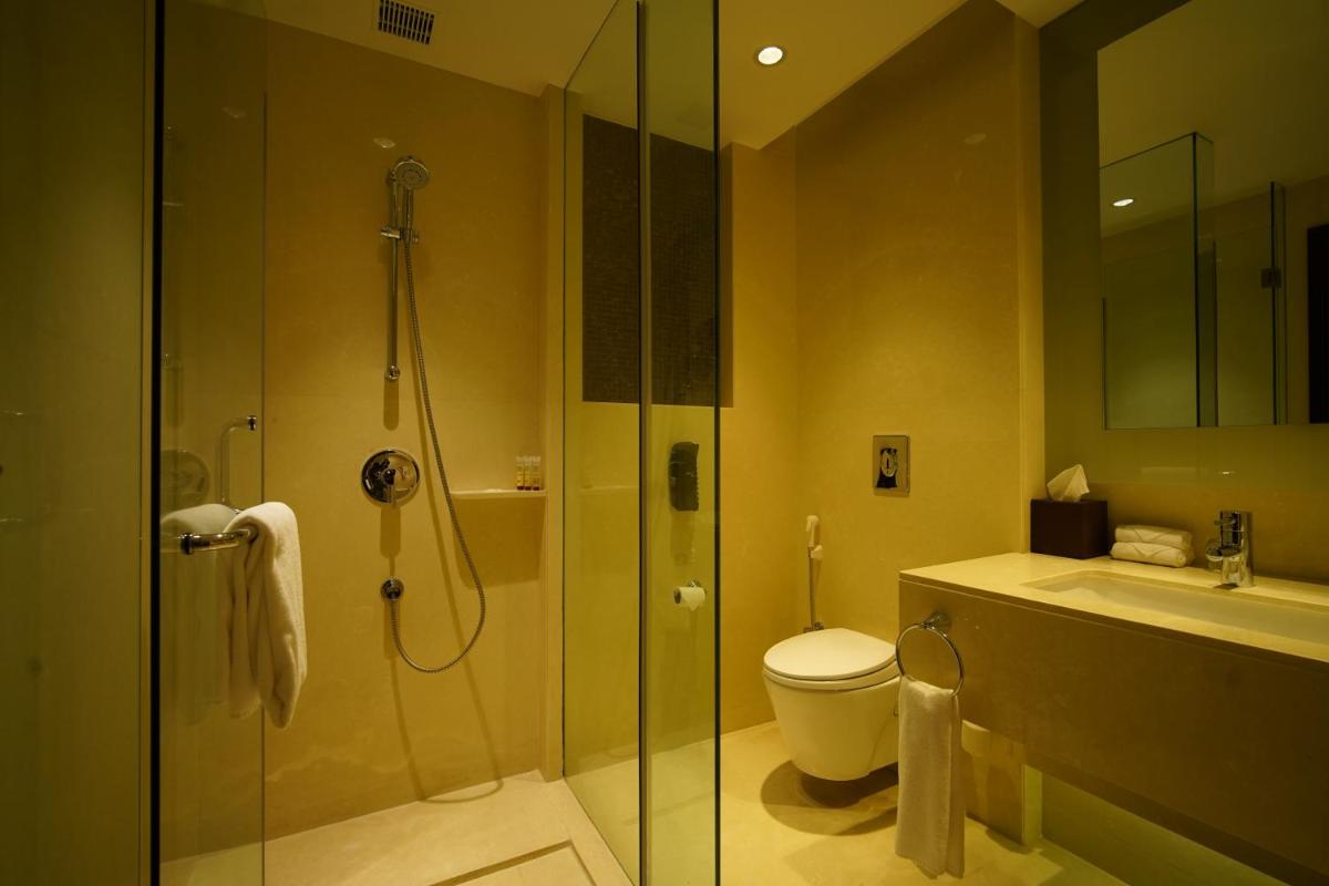 a bathroom with a shower and a toilet and a sink at Crowne Plaza Kochi by IHG in Cochin