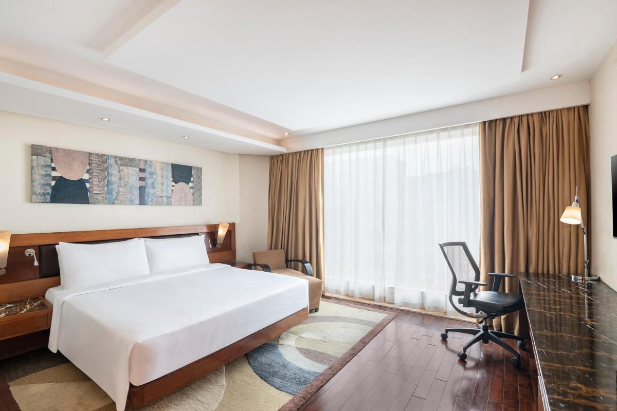 a bedroom with a white bed and a desk and a chair at Radisson Blu Kaushambi Delhi NCR in Ghaziabad