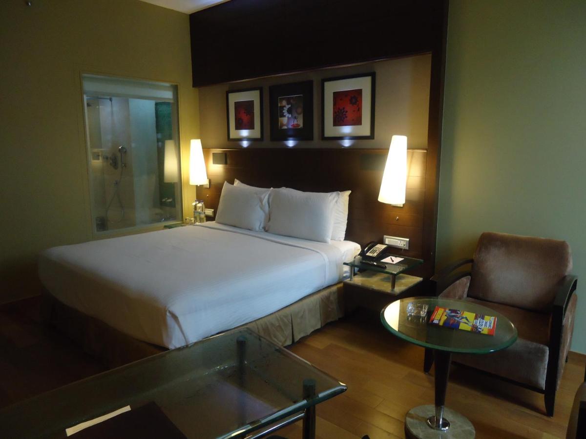 a hotel room with a bed and a chair and a table at Radisson Blu Atria Bengaluru in Bengaluru a hotel room with a bed and a chair and a table at Radisson Blu Atria Bengaluru in Bengaluru