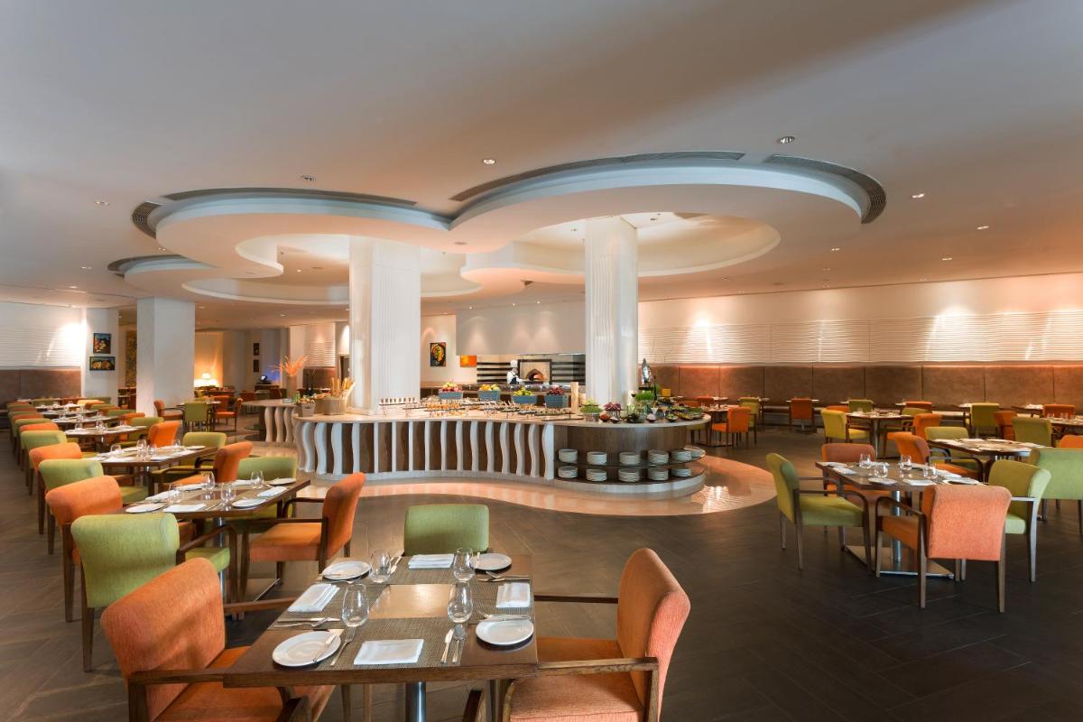 a restaurant with tables and chairs and a bar at Welcomhotel by ITC Hotels, Dwarka, New Delhi in New Delhi a restaurant with tables and chairs and a bar at Welcomhotel by ITC Hotels, Dwarka, New Delhi in New Delhi