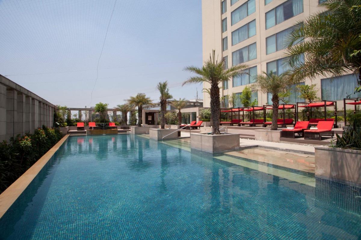a large swimming pool with red chairs and a building at Hyatt Regency Amritsar Hotel & Spa in Amritsar