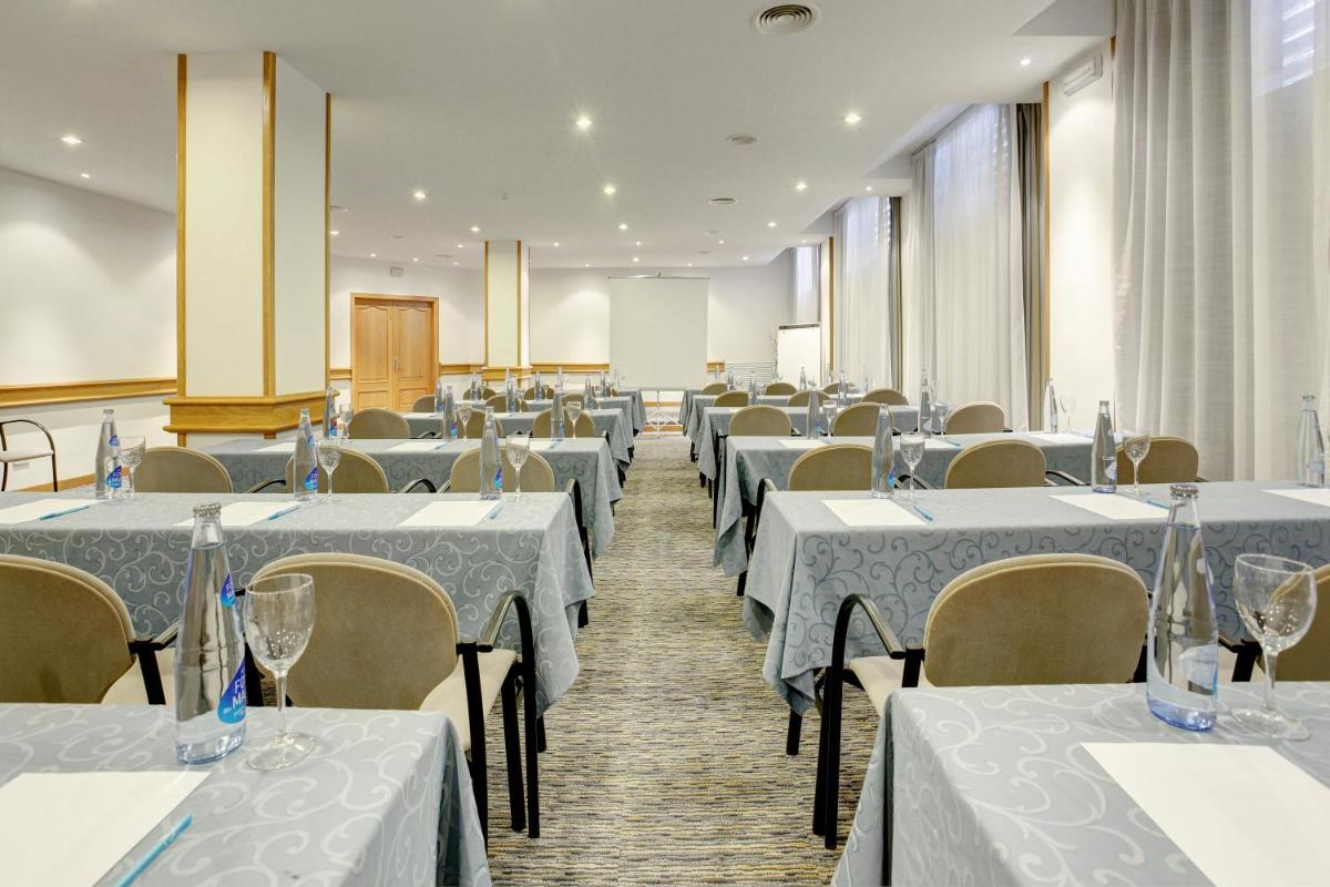 Un salón de banquetes con mesas y sillas blancas. en Grupotel Montecarlo, en Can Picafort 43 fotos más