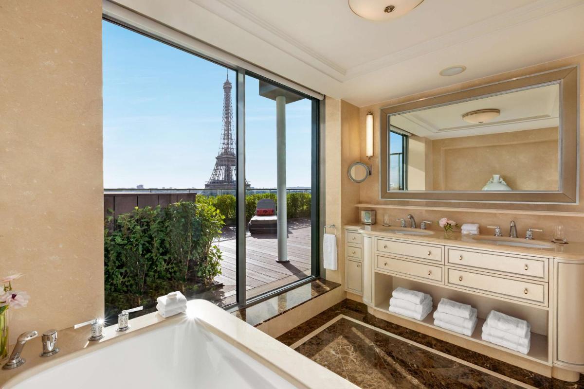 une salle de bains avec baignoire et une grande fenêtre donnant sur la tour Eiffel dans l'établissement Shangri-La Paris, à Paris