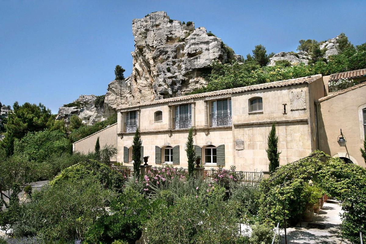 un bâtiment en pierre avec une montagne en arrière-plan dans l'établissement Baumanière - Les Baux de Provence, aux Baux-de-Provence