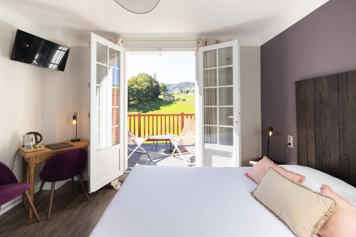 une chambre avec un lit blanc et un balcon dans l'établissement LOGIS Hôtel St Sylvestre, à Aldudes